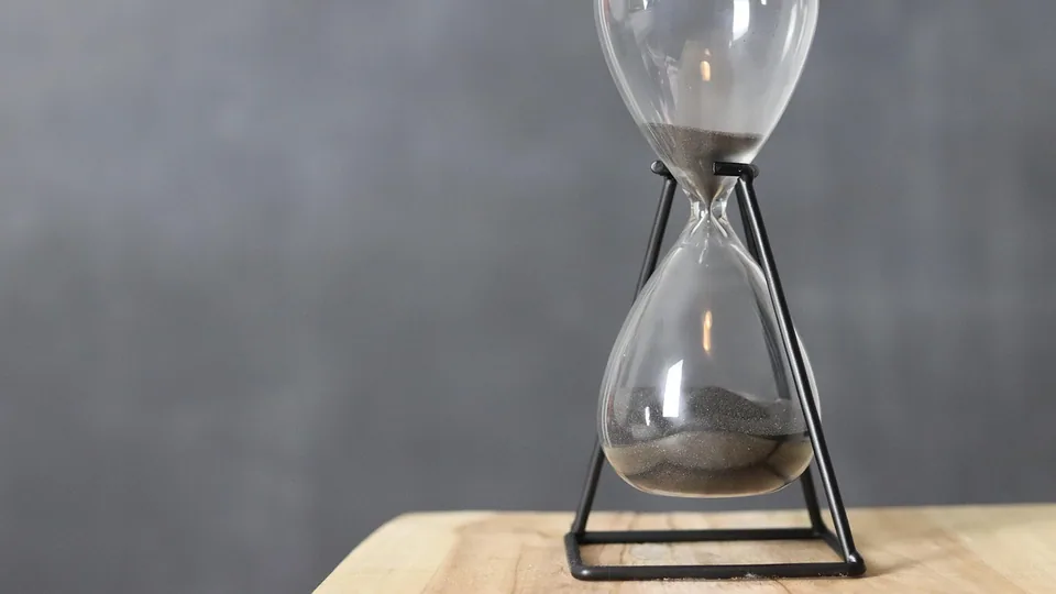 Timglas med rinnande sand mot en mörk bakgrund