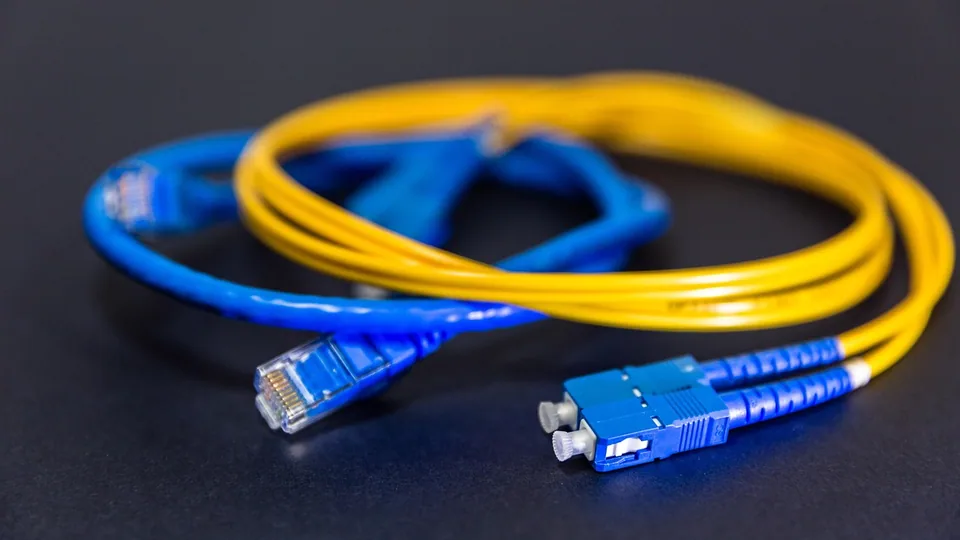 Nätverkskabel och fiberpatchkabel hoprullade bredvid varandra